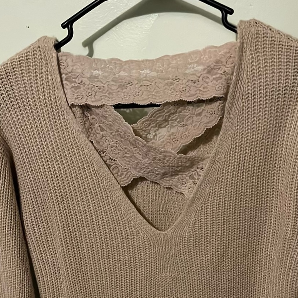 A tan knit sweater with beautiful lace bands on the back.